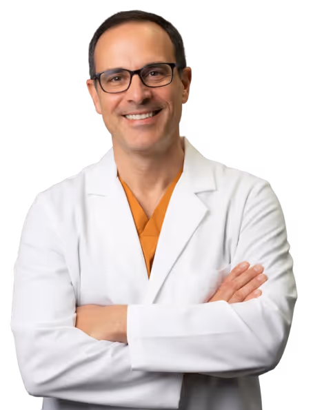 Smiling male doctor wearing glasses and a white coat with arms crossed.
